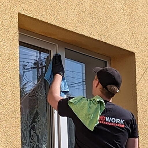 Pracownik firmy sprzątającej Solid Work myjący okno